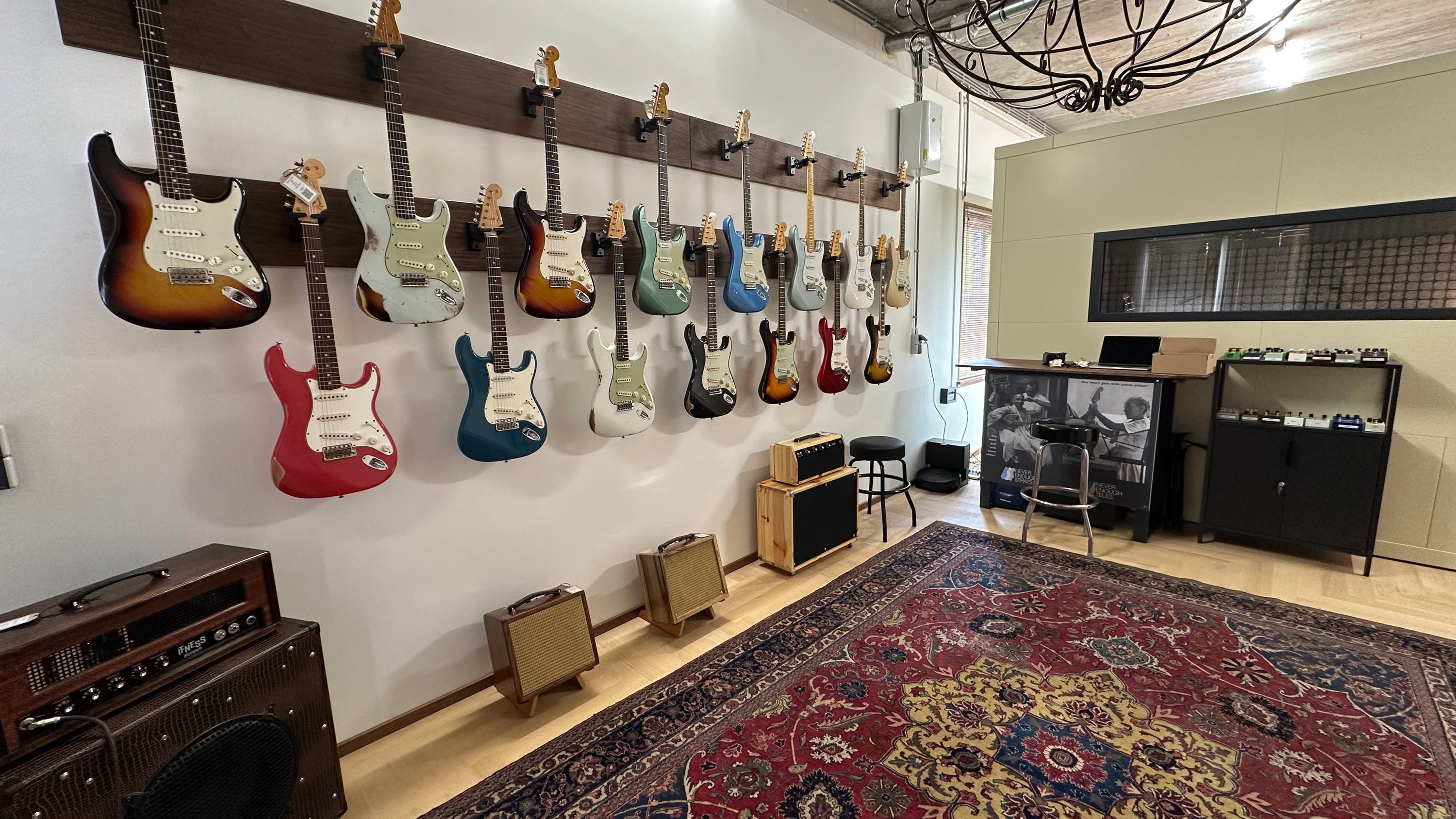 Guitar wall display in a music store with various guitars hanging on a rack.